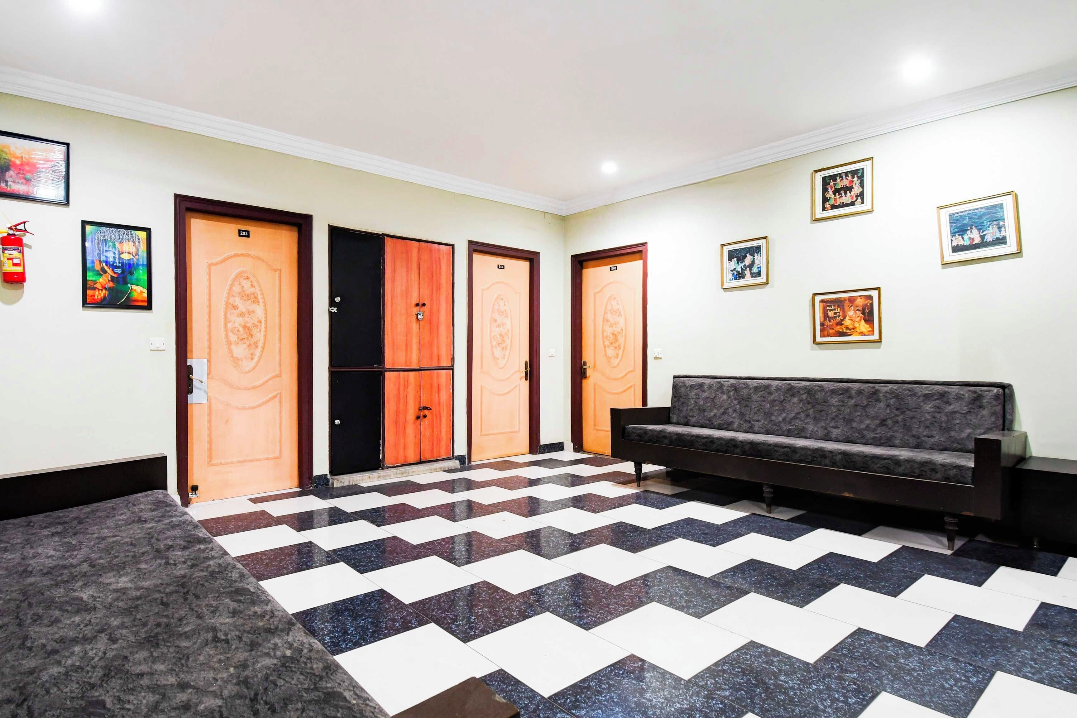 A lobby with a checkered floor, a sofa, and a fire extinguisher.