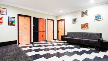 A lobby with a checkered floor, a sofa, and a fire extinguisher.