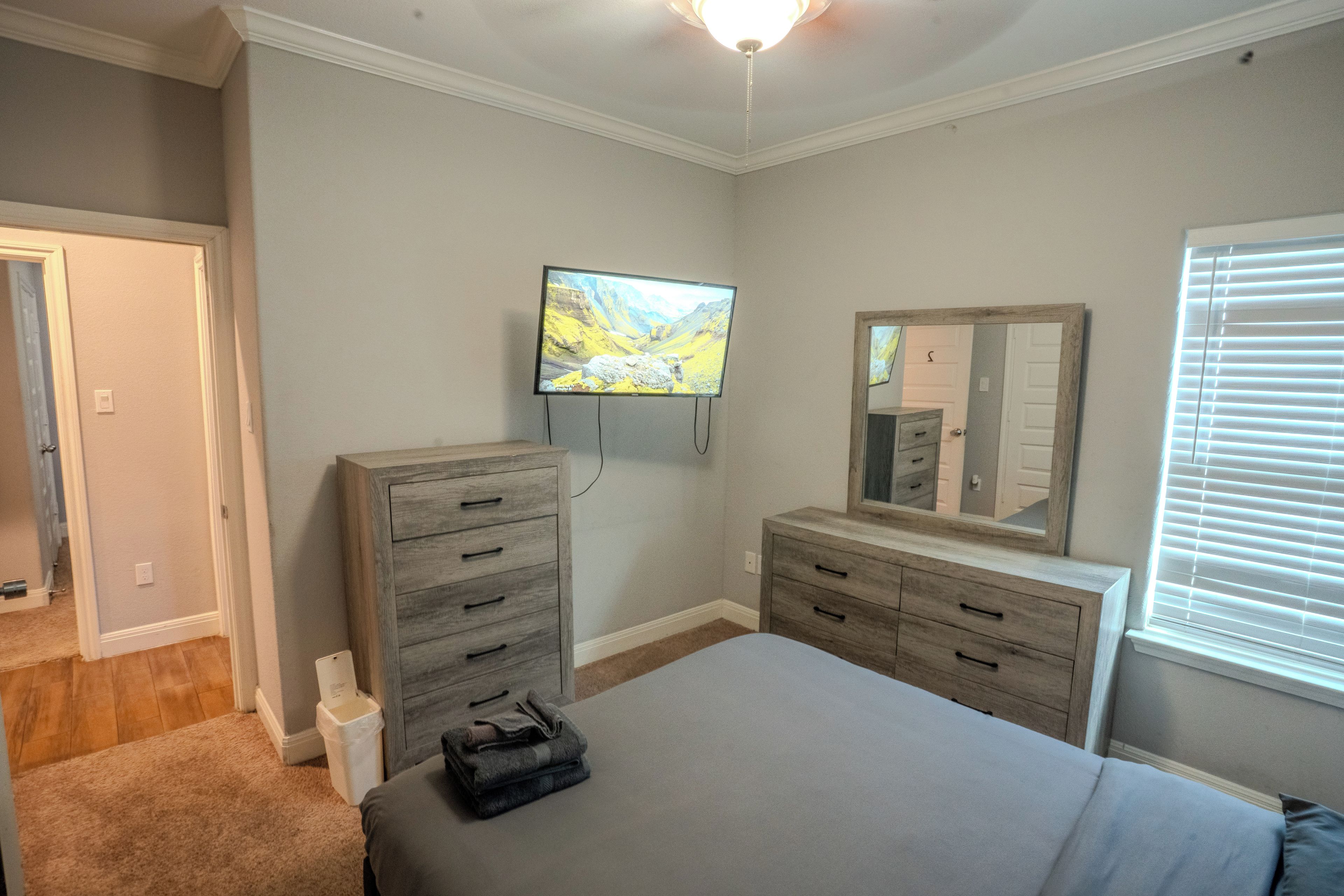 Ein Schlafzimmer mit Bett, Kommode, Fernseher und Spiegel.