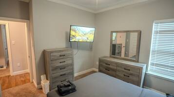 Ein Schlafzimmer mit Bett, Kommode, Fernseher und Spiegel.