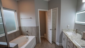 Une salle de bain avec une baignoire, un lavabo et une porte donnant sur une autre pièce.