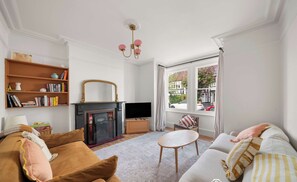 A bright living room features a light grey sectional sofa and a brown couch arranged around an oval wooden coffee table on a grey area rug. - Mildred House, Watford (Hertfordshire)