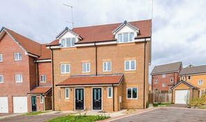  A modern three-story brick townhouse under an overhanging tiled roof, alongside a small paved area and a driveway leading to a detached garage. - 17 Colwick House, Rotherham (South Yorkshire)