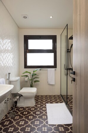 Ein Badezimmer mit Toilette, Waschbecken, Dusche und einem Fenster.