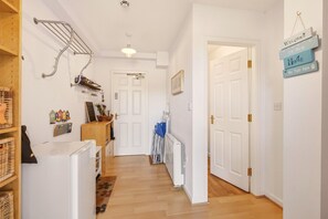 A hallway with a white door, a radiator, and a sign that says 'Welcome to our home by the sea.' - Bay View @ Waren Mill - North East Escapes (Waren Mill)