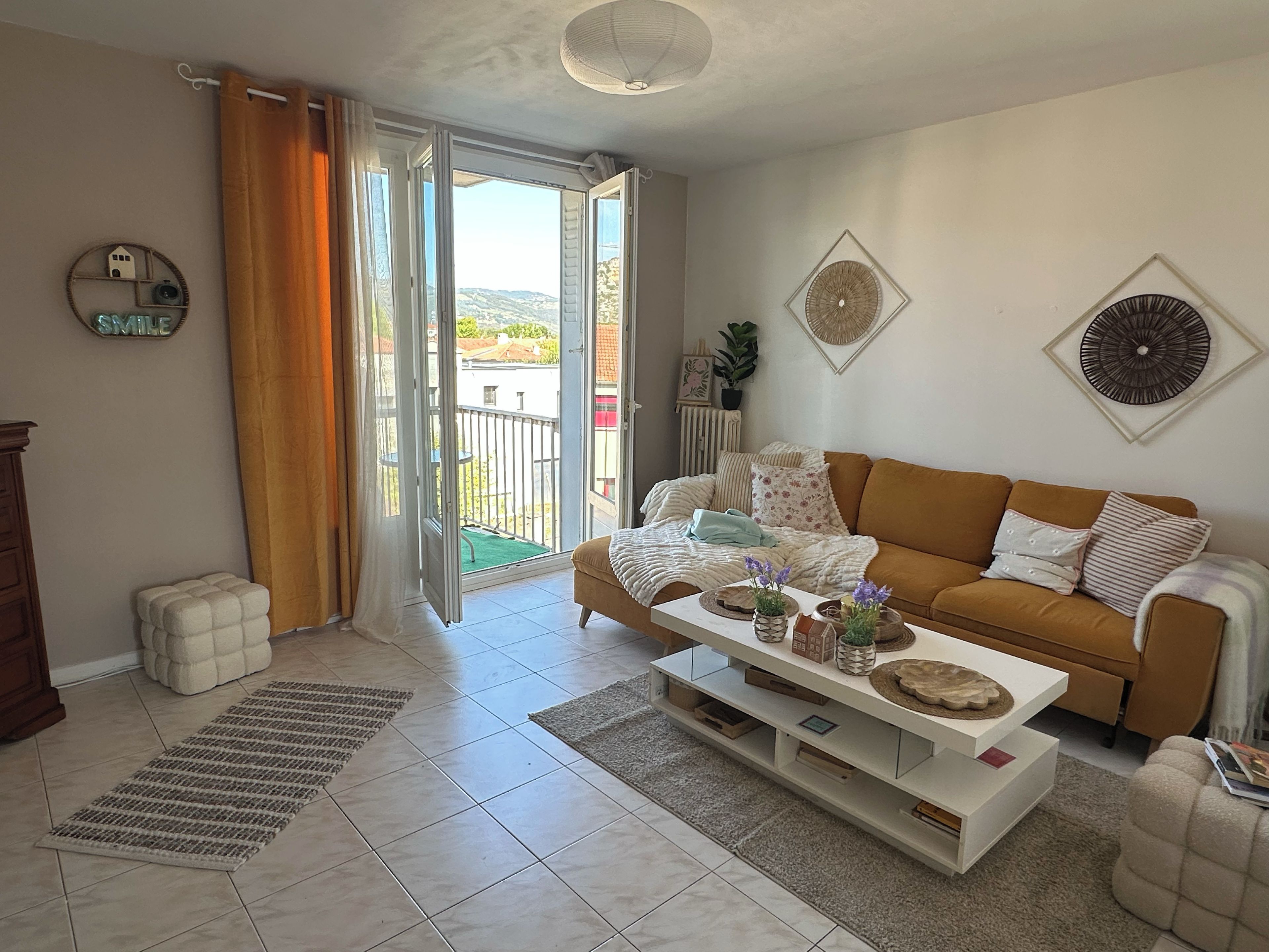 A living room with a sofa, coffee table, and a view through a sliding door to an outdoor area.