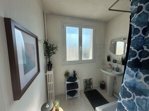 A bathroom with a white sink, a mirror, a window, and a framed picture on the wall. - 2 bedrooms • Balcony with a view of Crussol • Near Valence (Guilherand-Granges)