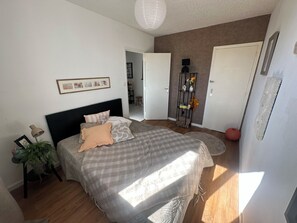 A bedroom with a bed, a bedside lamp, a potted plant, and a door leading to another room. - 2 bedrooms • Balcony with a view of Crussol • Near Valence (Guilherand-Granges)