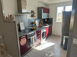A compact kitchen with a built-in washing machine, a microwave, and a refrigerator. - 2 bedrooms • Balcony with a view of Crussol • Near Valence (Guilherand-Granges)