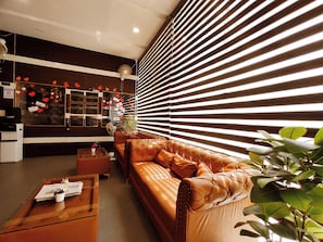 A modern interior with a leather sofa, a coffee table, and a large window with blinds.