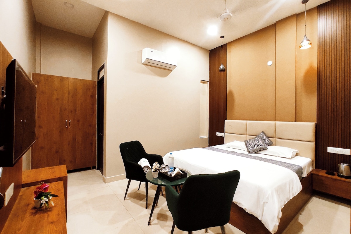 Habitación de hotel con cama, escritorio, silla, televisor y armario.
