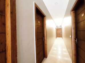 Un pasillo con puertas de madera y suelo de baldosas, que conduce a una habitación.