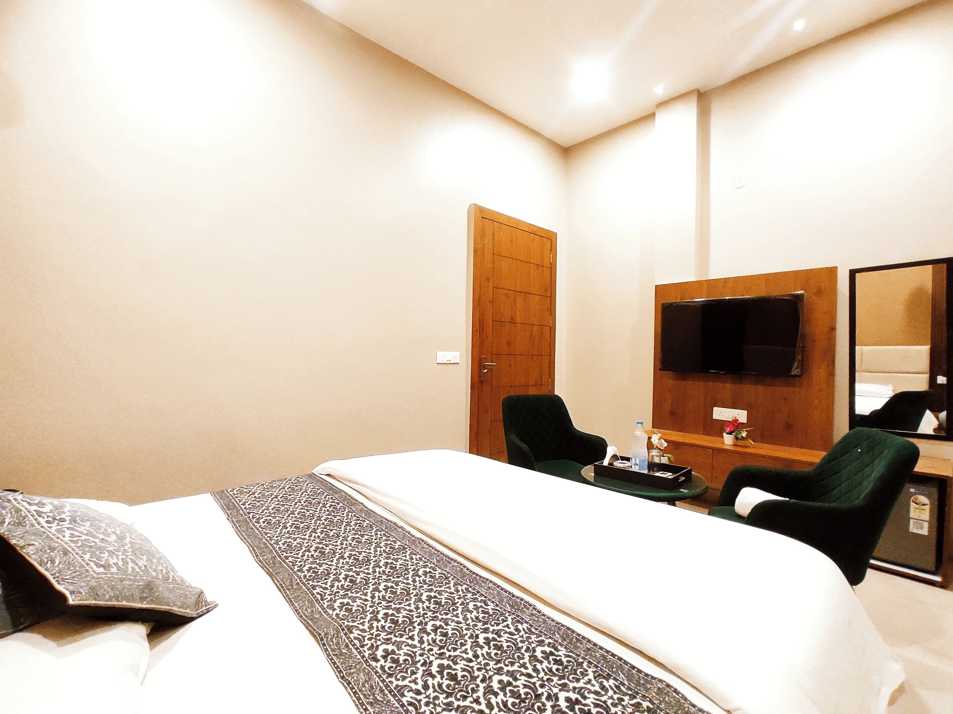 Une chambre d’hôtel comprenant un lit, un bureau avec une chaise, une télévision et un miroir.