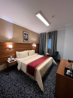 Una habitación de hotel con una cama, mesitas de noche, un escritorio y una silla.