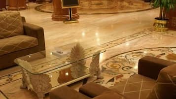 A hotel lobby with a reception desk, seating area, and a large plant.