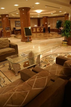 Un vestíbulo de hotel con una recepción, un área de estar y una planta grande.