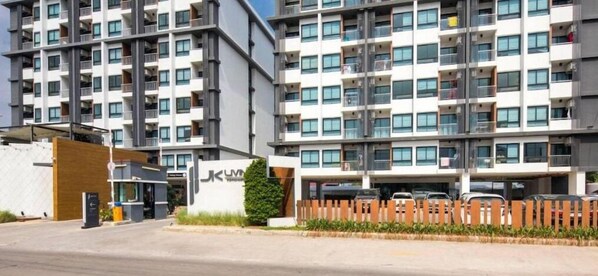 Un immeuble résidentiel à plusieurs étages, doté de balcons, d’une entrée sécurisée et d’un espace de stationnement.