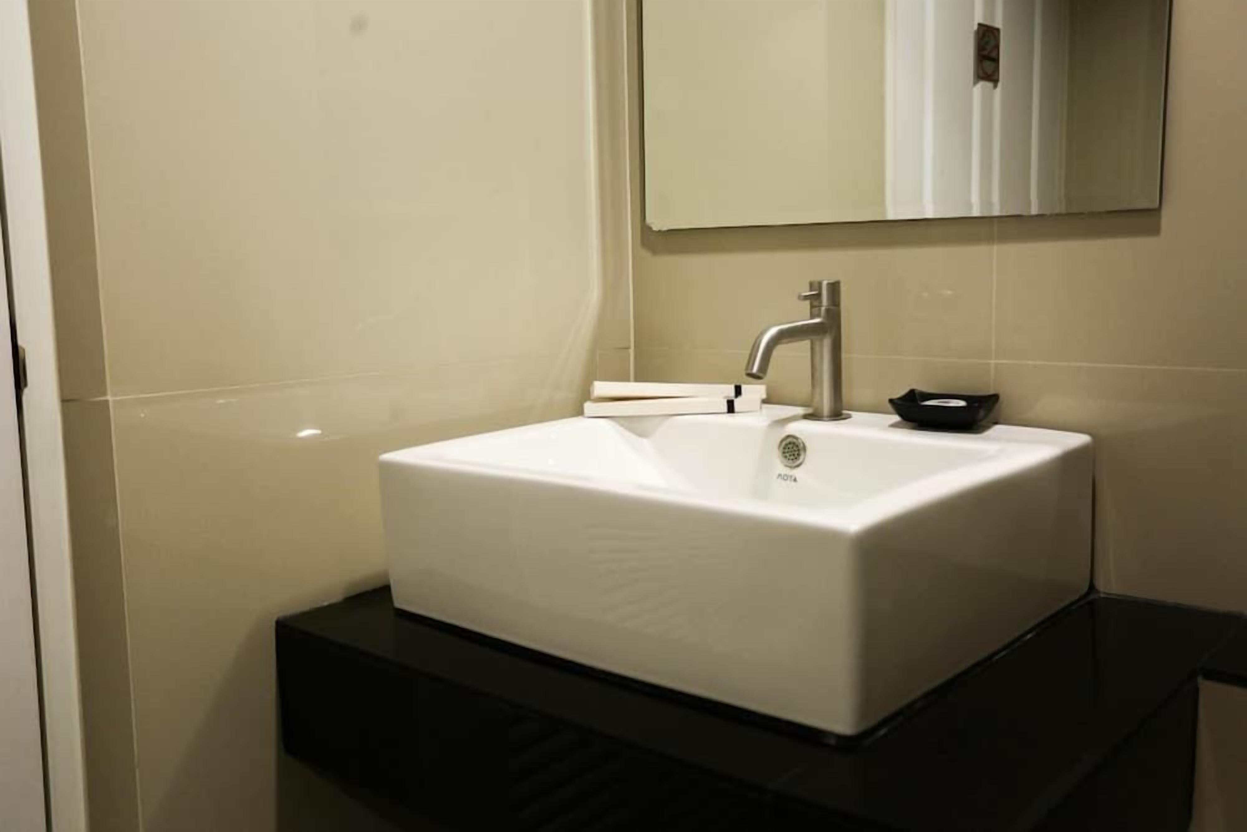 A bathroom with a white sink, a mirror, and a black countertop.