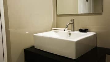 A bathroom with a white sink, a mirror, and a black countertop.