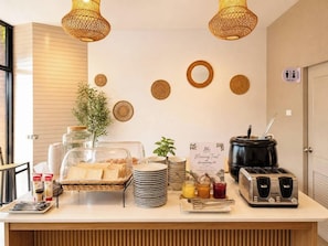 Disposição de buffet de café da manhã, incluindo torradeira, potes com patês e uma placa com a inscrição 'JK Morning Treat'.