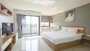 Habitación de hotel moderna con una cama grande, televisor, escritorio y balcón con cortinas.