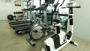 Un gimnasio con diverso equipo de ejercicio, incluyendo cintas de correr, una máquina elíptica y una bicicleta estática.
