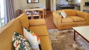 Ein Wohnzimmer mit einer Couch, einem Esstisch und einer Küche im Hintergrund.