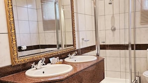 Ein Badezimmer mit zwei Waschbecken, einem großen Spiegel und einer Duschkabine aus Glas.