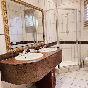 Un baño con dos lavamanos, un espejo grande y una cabina de ducha de vidrio.