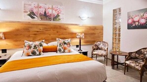 Ein Hotelzimmer mit einem Bett, zwei Nachttischen, einem Sessel, einem kleinen Tisch und Wandleuchten.