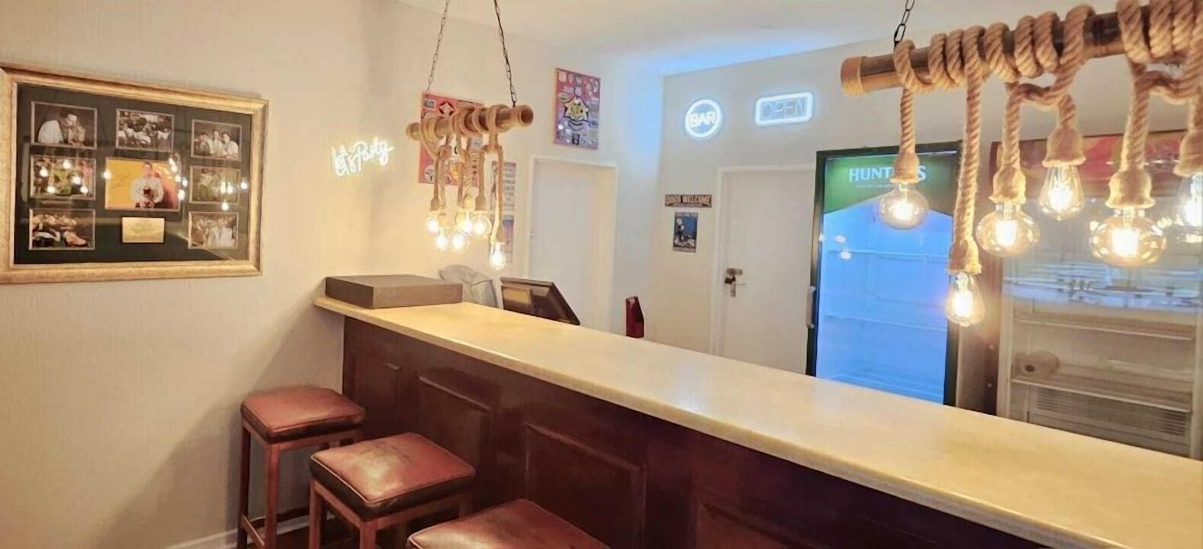 A bar area with a counter, stools, and a hanging light fixture.