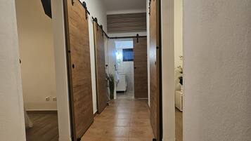 A hallway with a tiled floor, wooden doors, and a ceiling light.