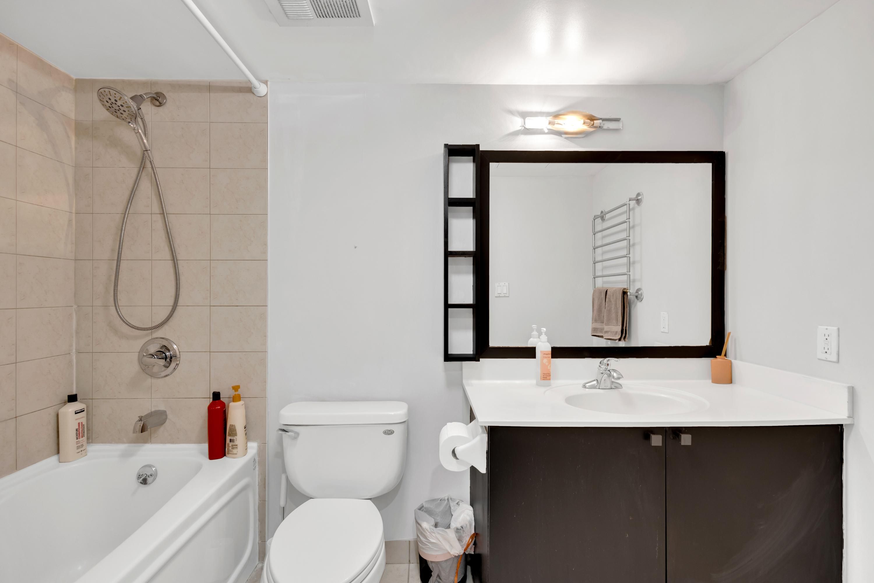 Un baño moderno con bañera, inodoro, lavabo y un espejo grande.