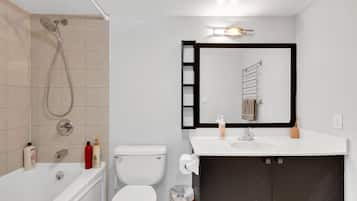 Un baño moderno con bañera, inodoro, lavabo y un espejo grande.