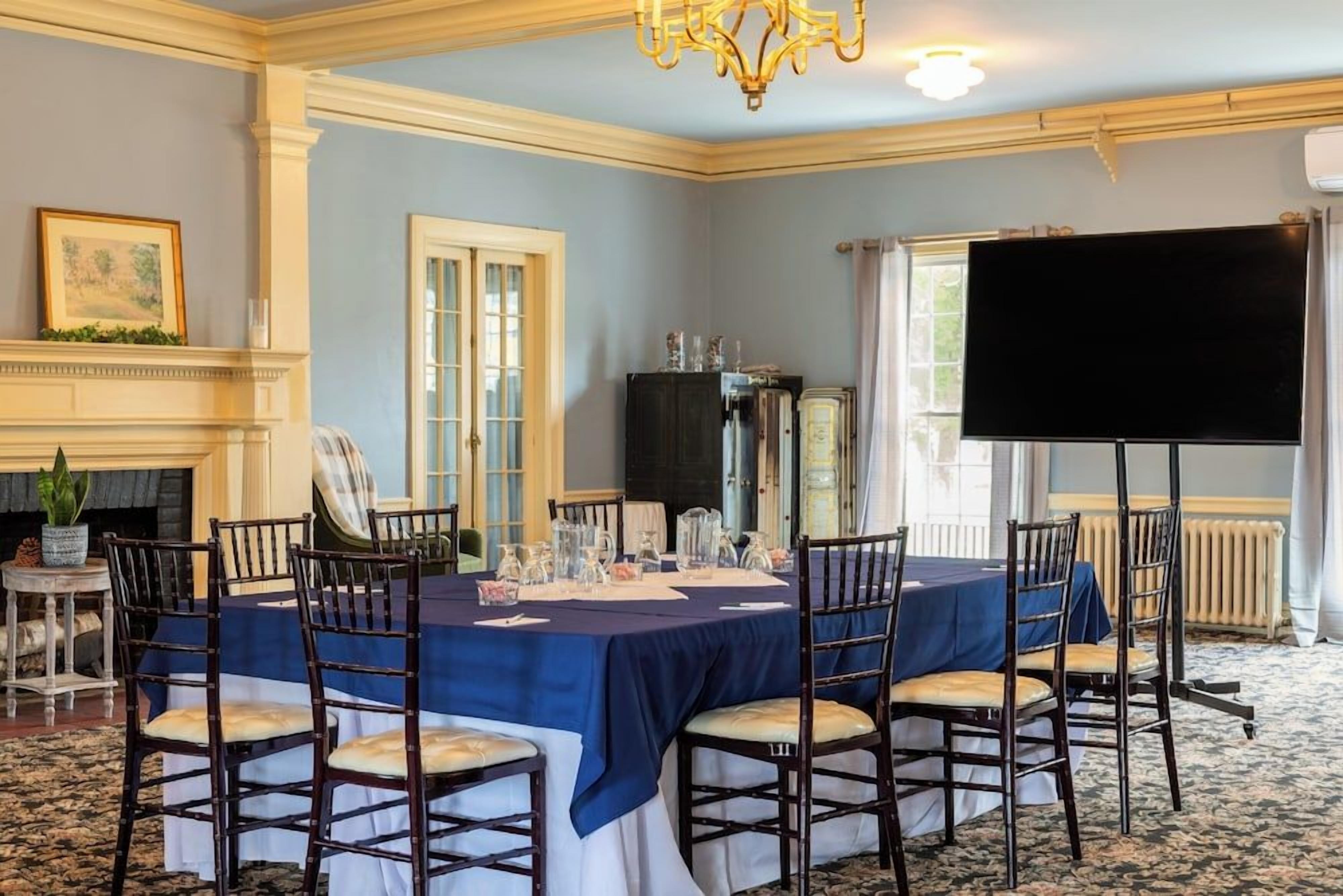 A conference room with a long table, chairs, a projector screen, and a fireplace.