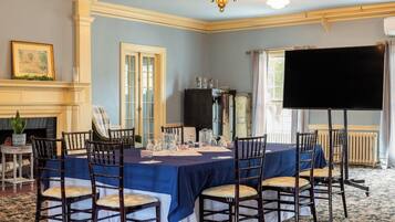 A conference room with a long table, chairs, a projector screen, and a fireplace.