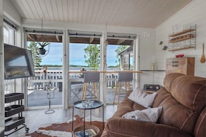A cozy living room with a brown leather sofa, a flat-screen TV, and a wooden coffee table. - Lakeside Retreat on Lake Laxsjön – Lake Views, Kayaks & Private Heated Terrace (Dals Långed)