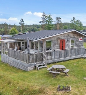 Eine rustikale Holzhütte mit einer Terrasse, einer Laube und einem Picknicktisch.