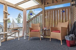 Ein Holzinterieur mit Korbmöbeln, einem kleinen Tisch und Blick ins Freie.