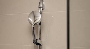 Eine Dusche mit chromfarbenem Wasserhahn und Handbrause.