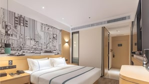 A hotel room with a large bed, a desk with a telephone, and a wall-mounted TV. - City Comfort Inn Xingtai Wanda (Xingtai)