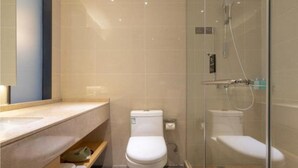Un bany modern amb dutxa envidriada, un vàter blanc i un lavabo amb mirall.
