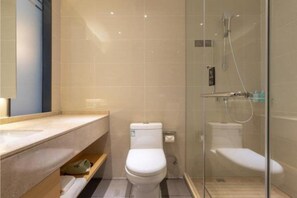 Ein modernes Badezimmer mit einer Duschkabine, einer weißen Toilette und einem Waschtisch mit Spiegel.