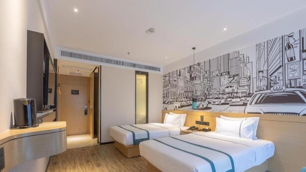 A hotel room with two beds, a flat-screen TV, a coffee machine, and a cityscape mural on the wall. - City Comfort Inn Xingtai Wanda (Xingtai)