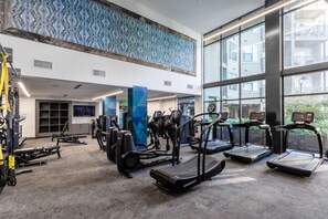 A gym with treadmills, weight machines, and a large window overlooking a residential area. - Locale Nashville - Music Row (Nashville)