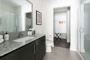 A modern bathroom with a granite countertop, a toilet, a shower area, and a framed picture on the wall. - Locale Nashville - Music Row (Nashville)