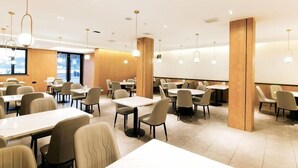 Uma sala de jantar moderna com mesas, cadeiras, detalhes em madeira e iluminação pendente.