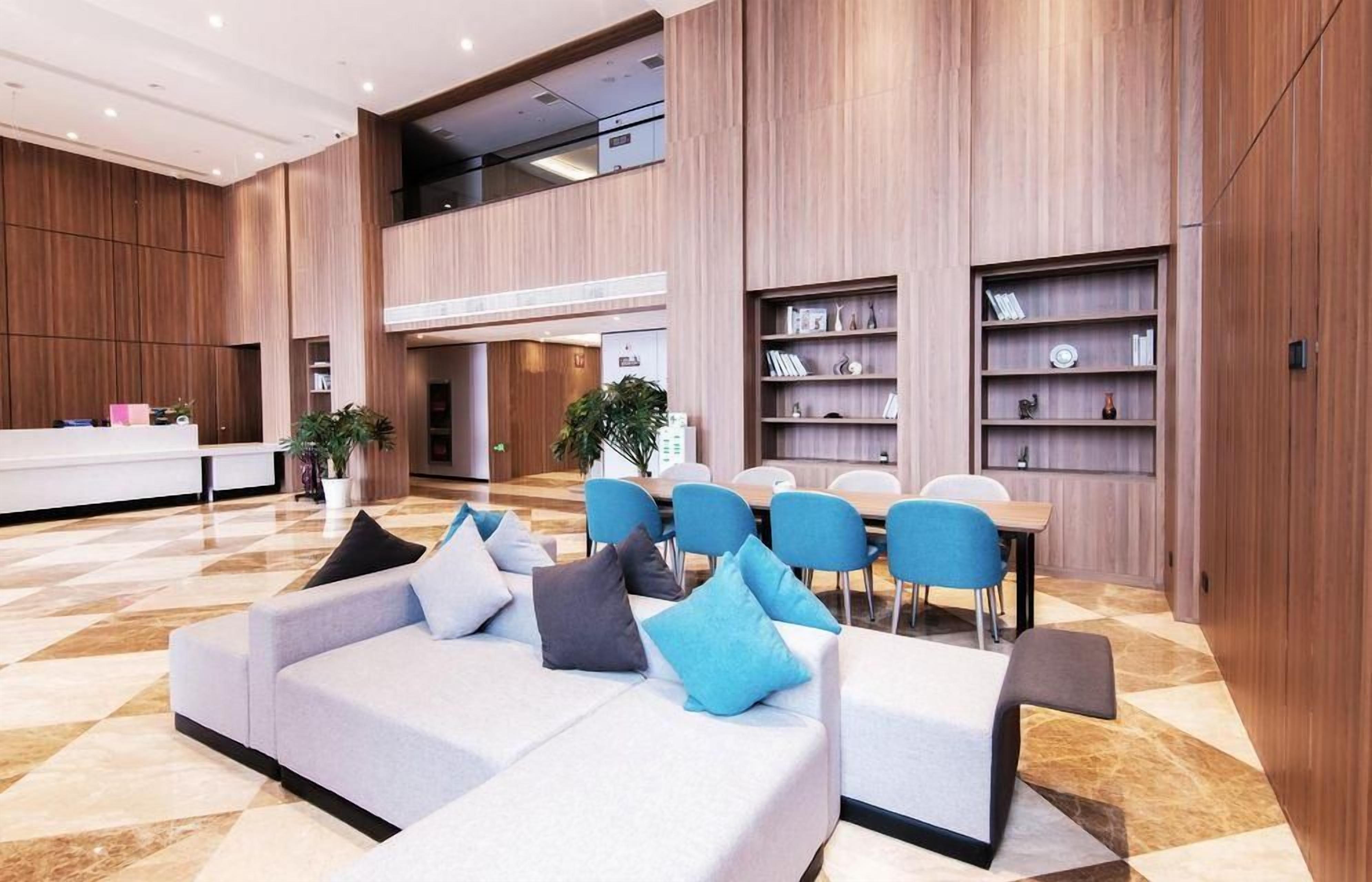 A modern hotel lobby with a reception desk, seating area, and built-in bookshelves.