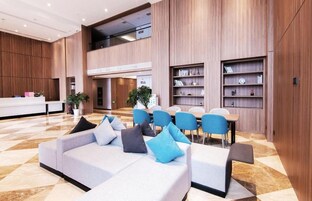Un moderno vestíbulo de hotel con mostrador de recepción, zona de estar y estanterías integradas.