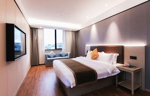 A modern hotel room with a large bed, a bedside table, a TV mounted on the wall, and a window with a view of the city. - GYA Ningbo Xiangshan Shipu Hotel (Ningbo)